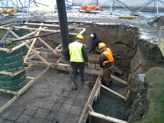 Construction workers wearing safety vests working on foundation of building